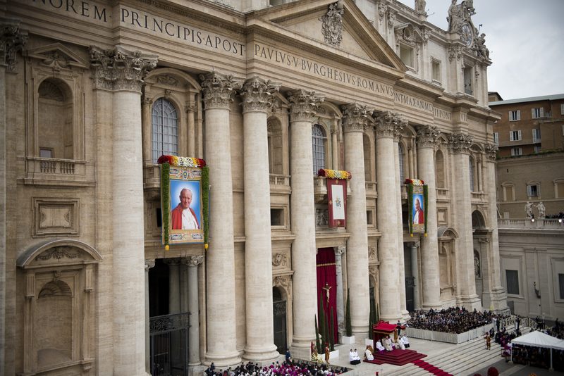 Crowds in St. Peter's Square during the 2014 canonization Mass of John XXIII and John Paul II, with their portrait banners on the basilica facade