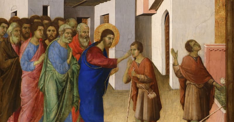 A medieval panel painting of a narrow street of pale buildings. At the center Christ, in a blue mantle over red with a gilded halo, reaches out to touch the eyes of a man in a russet cloak who holds a long walking staff, while a crowd of disciples presses behind him at the left. At the right the same man stands a second time, his staff lowered, both hands raised and his face turned upward.