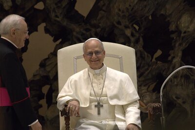 Pope Leo XIV, seated and smiling during his audience with the media on 12 May 2025 — the American-born pope (Robert Francis Prevost) who sealed the Holy Door of the 2025 Jubilee at Epiphany 2026