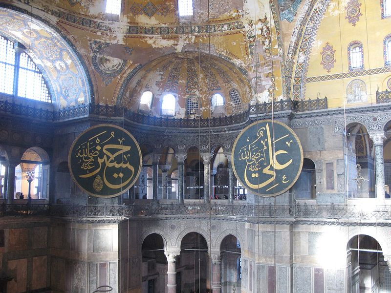 Interior view of Hagia Sophia in Istanbul showing the dome, calligraphic medallions, and the building's Byzantine and Ottoman architectural fusion
