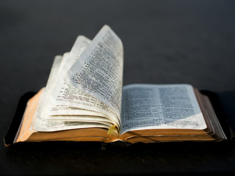 An open Bible resting on a table, its pages softly lit—a symbol of the scriptural authority both Calvinists and Catholics affirm, though they disagree on how Scripture relates to Tradition