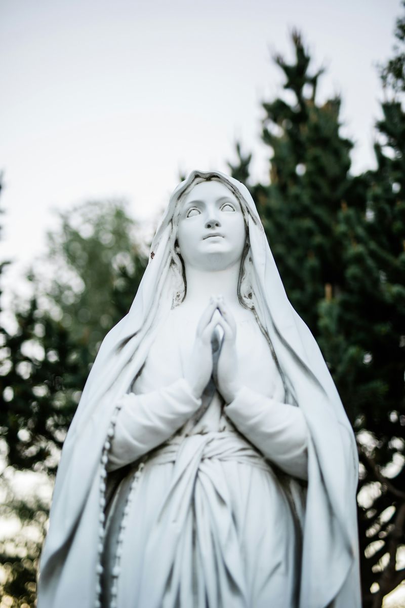 A ceramic statue of the Virgin Mary, hands clasped in prayer