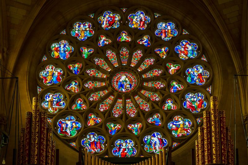 Rose window in a cathedral, its stained glass panels depicting scenes from the Christian tradition shared by both Calvinism and Catholicism
