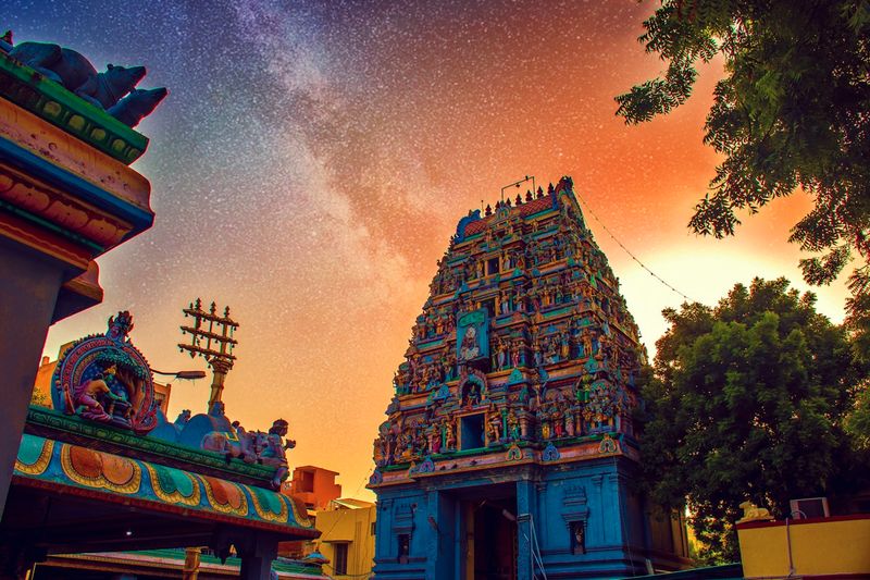 A colorful Hindu gopuram temple tower against a twilight sky
