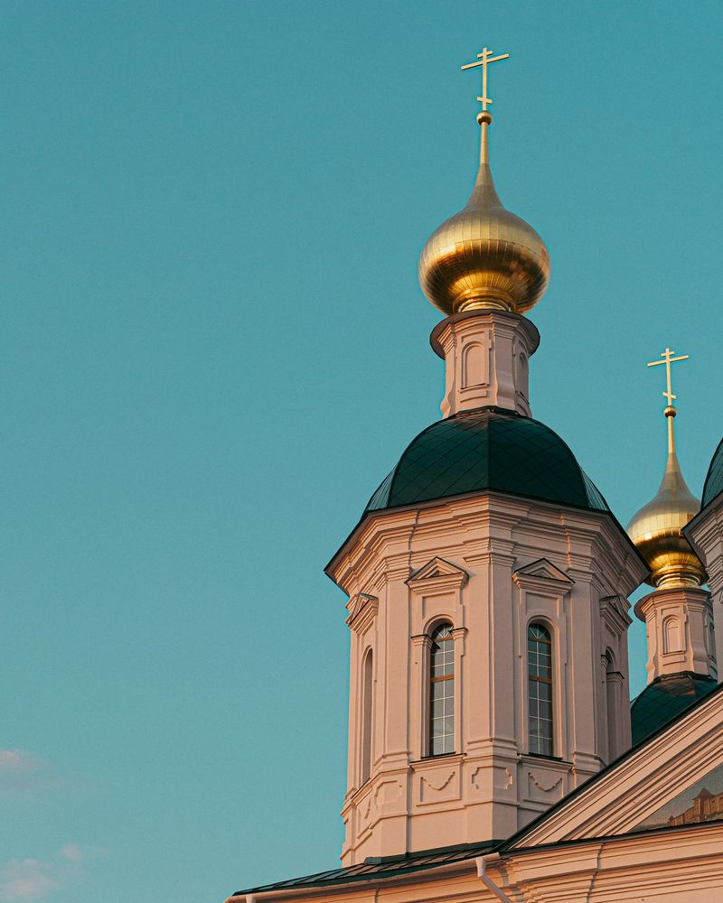 Golden onion domes topped with Orthodox crosses on a Russian church at sunset