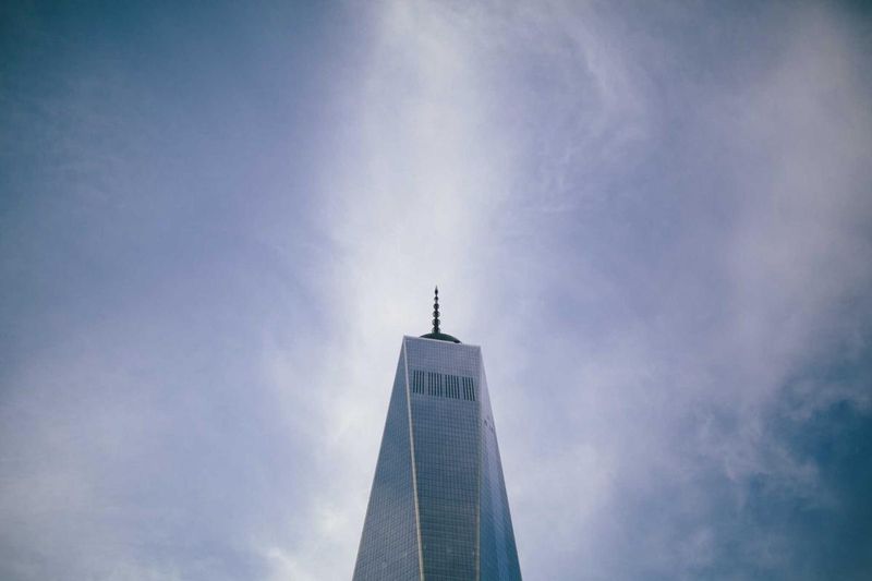 One World Trade Center tower rising against an overcast sky — a symbol of resilience amid suffering
