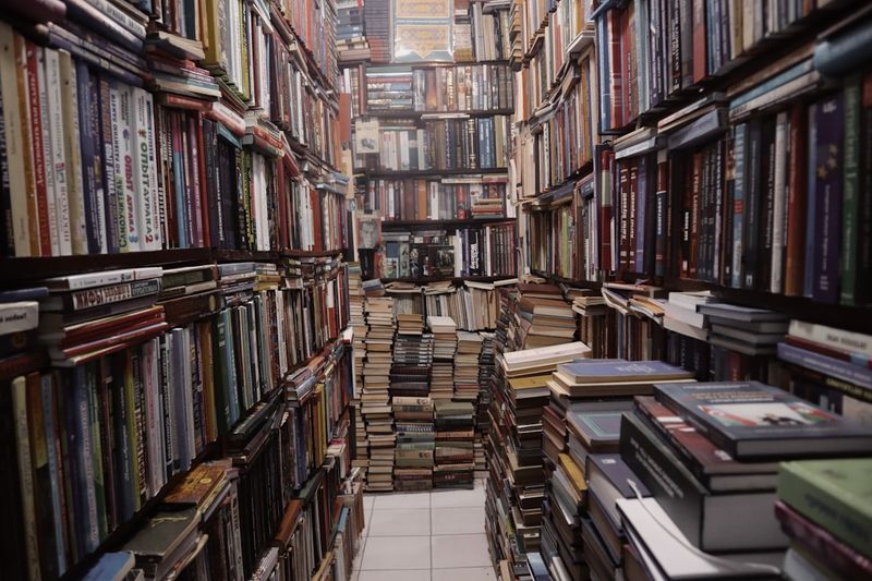 A narrow aisle in a used bookstore lined floor to ceiling with books