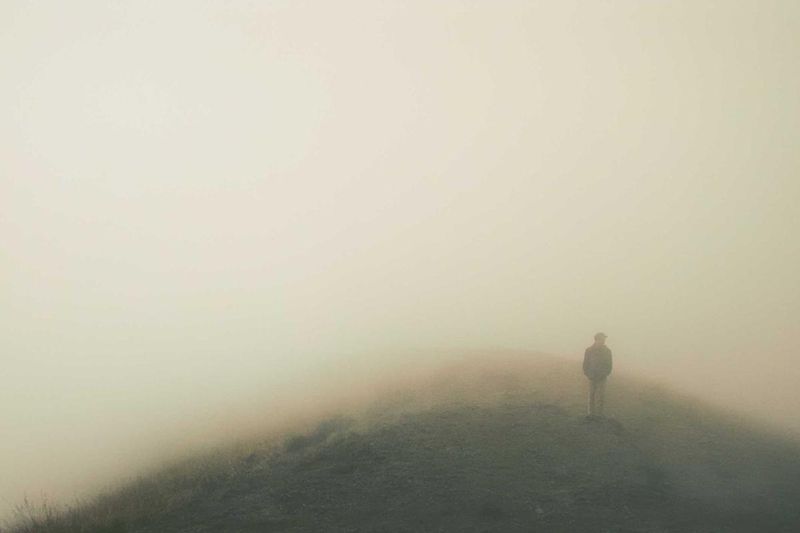 A solitary figure standing on a misty hilltop, evoking the uncertainty of estate planning for unexpected loss