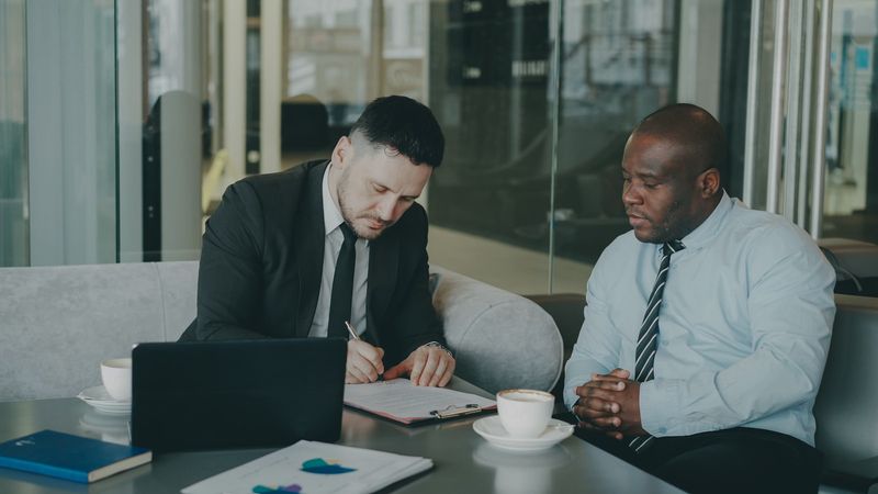 Two attorneys signing a corporate proxy agreement at a conference table