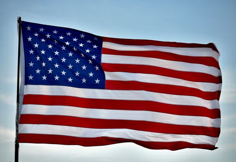 American flag flying against a clear sky, marking graduation from the Army JAG School and commissioning into the JAG Corps