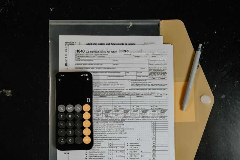 Calculator and pen resting on IRS tax forms on a desk