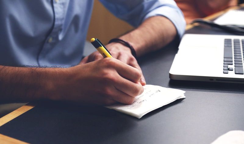 A person writing notes with a pen at a desk — representing the personal statement writing process