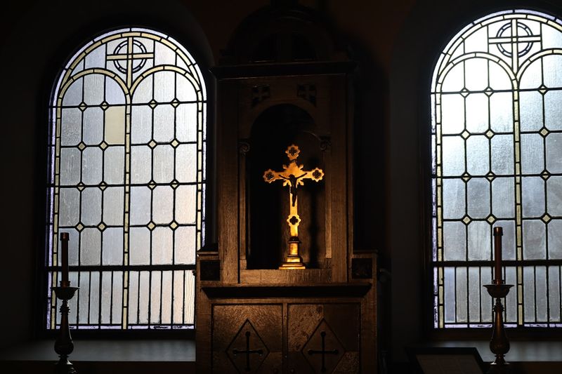 A cross and stained glass windows inside a seminary chapel sacristy