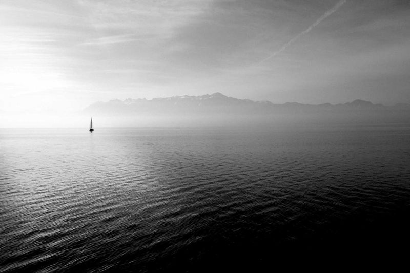 A lone sailboat on calm water at dawn with a misty mountain range in the distance — evocative of the quiet pause that a stay pending appeal places on judgment enforcement while the appellate court takes the case under advisement.